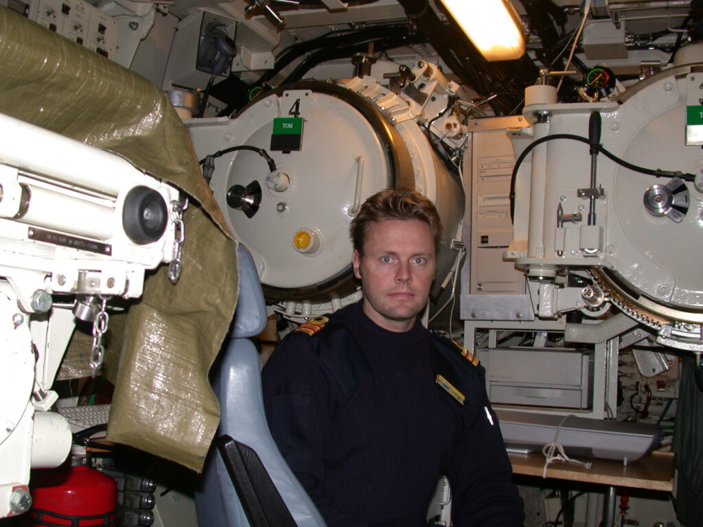 Dr Gert Tollesson in Swedish Navy uniform, seated in a submarine torpedo room